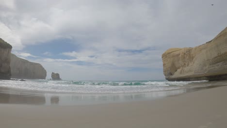 Wide-view-shot-of-beautiful-sand,-secluded-beach-and-incredible-sandstone-cliffs---Tunnel-Beach-Track,-Dunedin