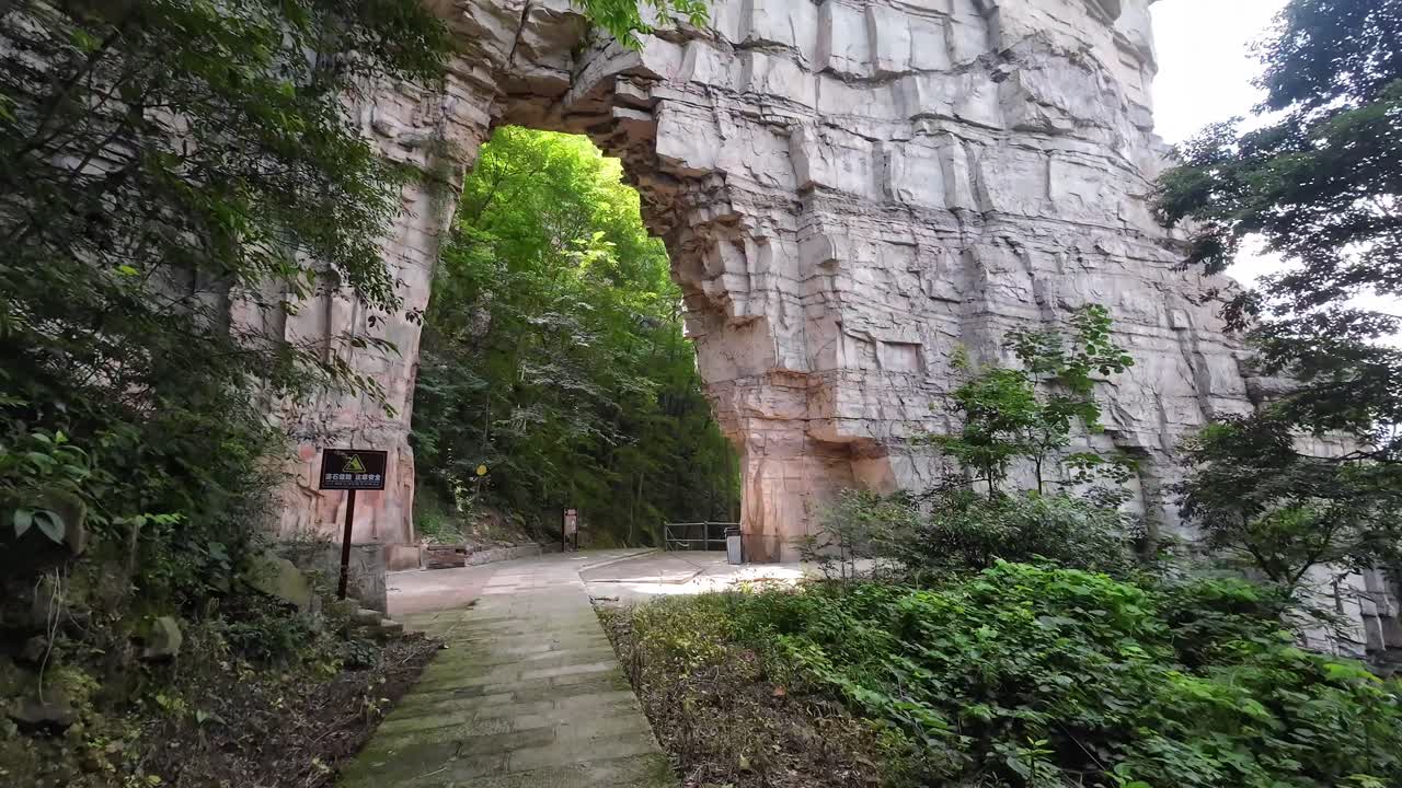 Camera angle elevates revealing massive stone arch and dense forest in Zhangjiajie National Park, China