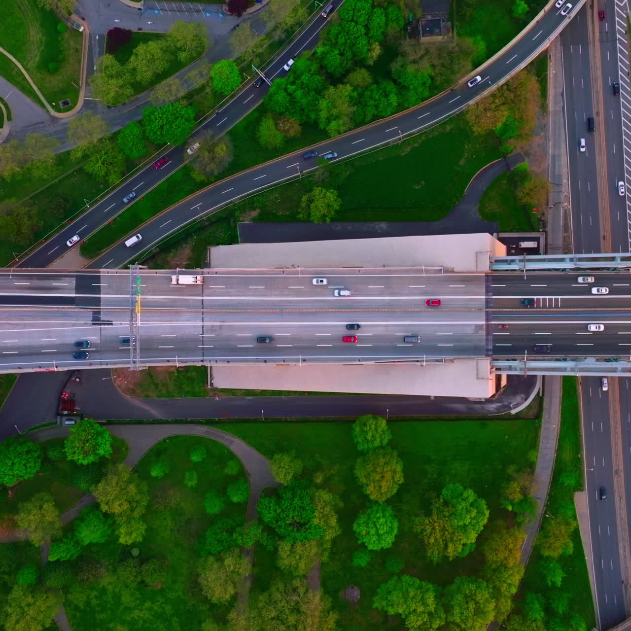 Motorways crossing each other and green park area. Cars running quickly over the roads in big city