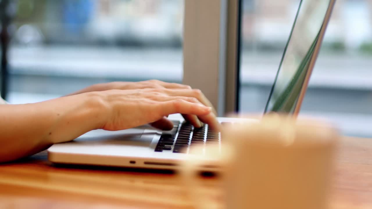 Businesswoman using laptop with coffee cup on table