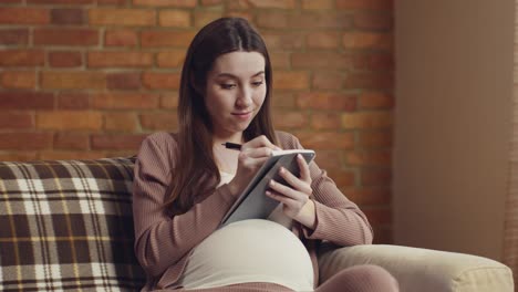 pregnant woman writing in a notebook at home