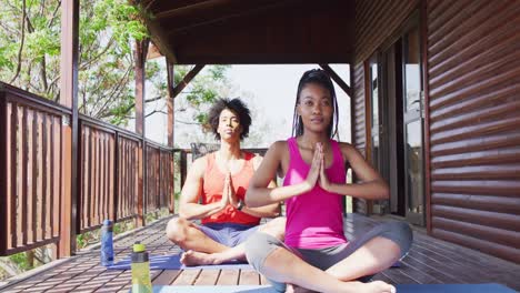 feliz pareja afroamericana haciendo yoga y meditando en una cabaña de madera, cámara lenta