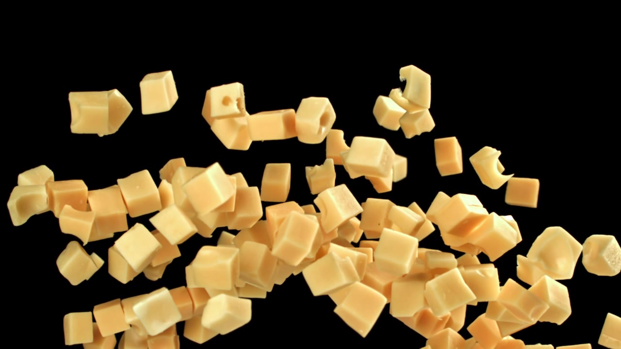 Movimento rallentato di cubetti di formaggio che cadono e galleggiano su sfondo nero