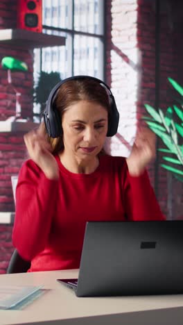 vertical video mature person having fun solving her work tasks with headset on at desk