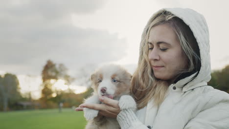 The-owner-of-the-puppy-holds-the-pet-in-his-arms.-Walking-together-in-the-autumn-park