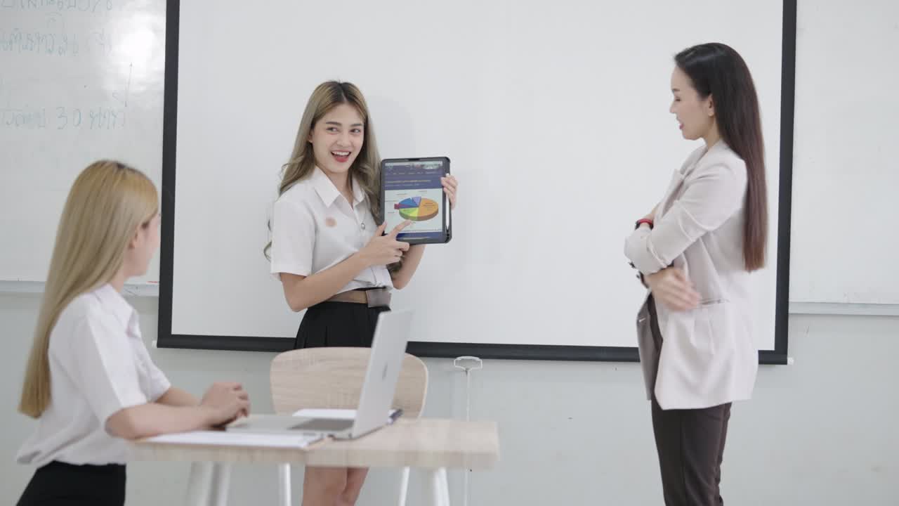группа азиатских женщин-студентов университета объясняют и представляют с женщиной-учителем профессором в классе