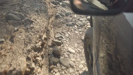 Low-close-up-shot-of-a-tire-off-road-driving-over-rocks
