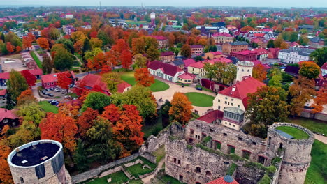 Aerial-view-of-an-iconic-medieval-castle-called-Cēsis-Castle-in-Latvia-surrouned-by-autumnal-trees-at-daytime
