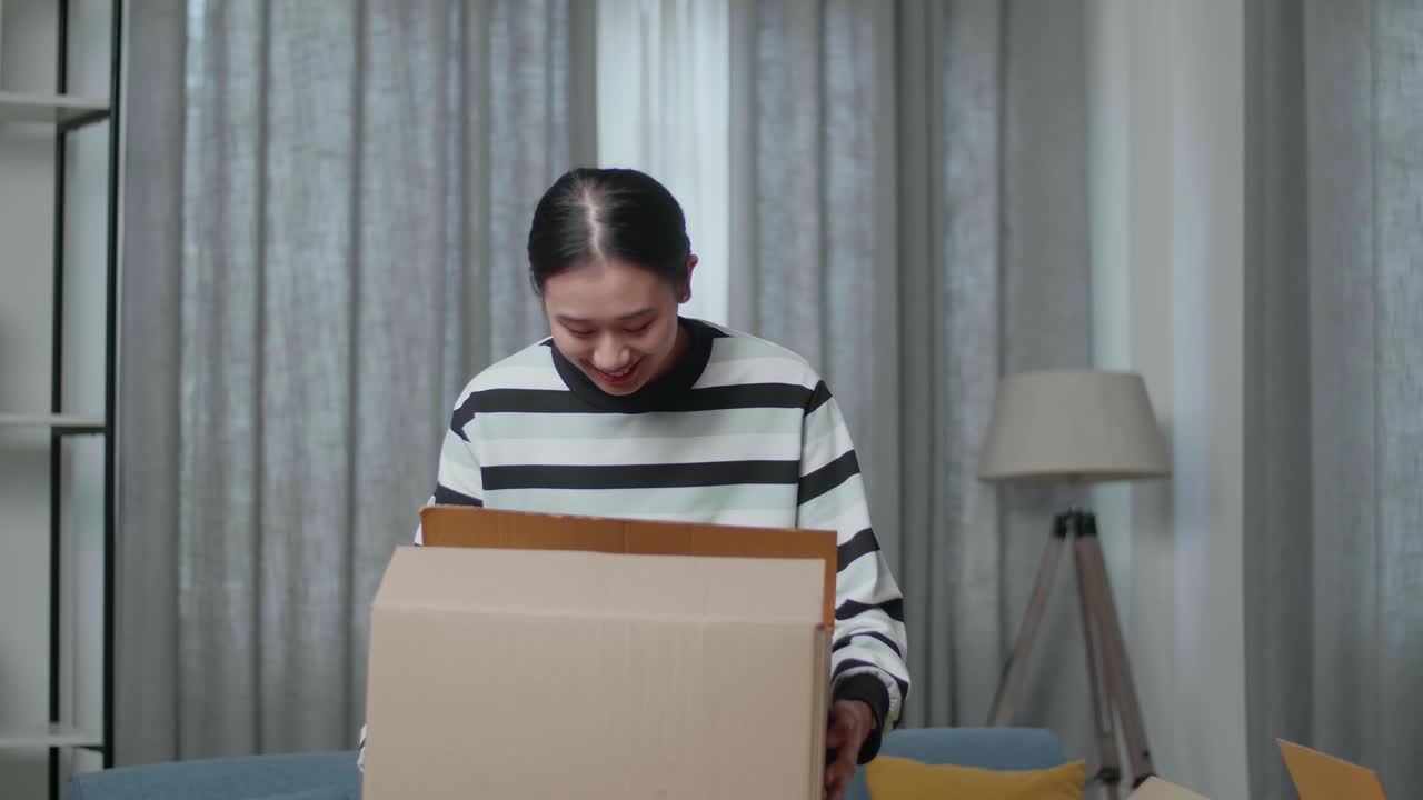 mujer emocionada desempaquetando cajas en su nuevo hogar