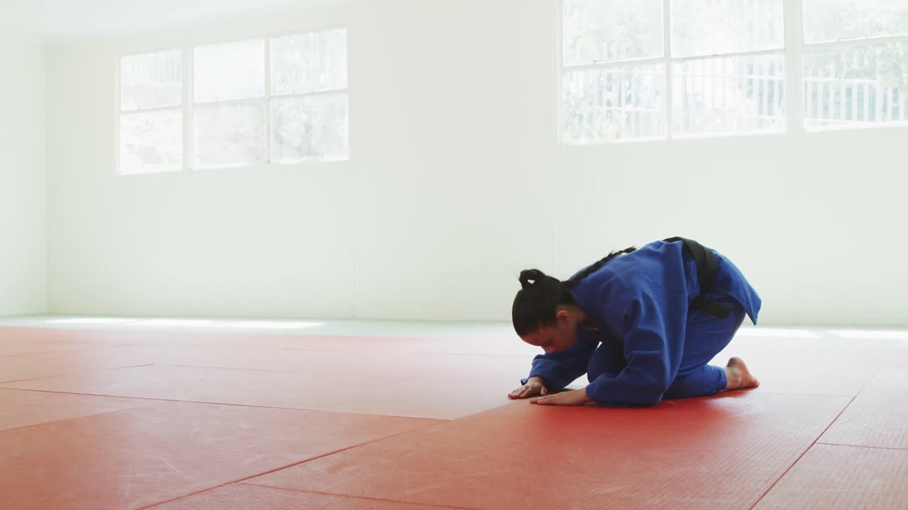 Kneeling judoka saluting on the judo mat