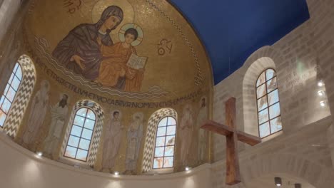 a church with a cross hanging from the ceiling in dormition abbey, jerusalem old city.