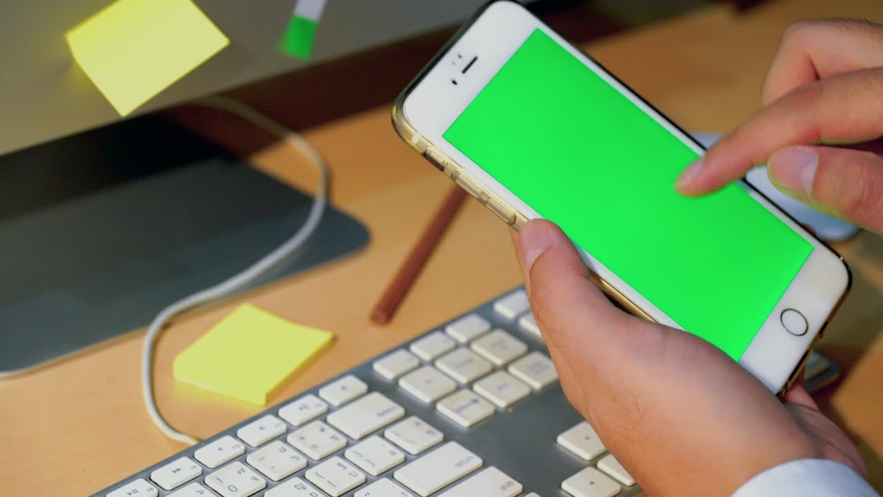 hombre de negocios tocar un teléfono inteligente en pantalla verde, computadoras y equipos de oficina, él estaba presionando el teclado, resolución 4k 30fps.