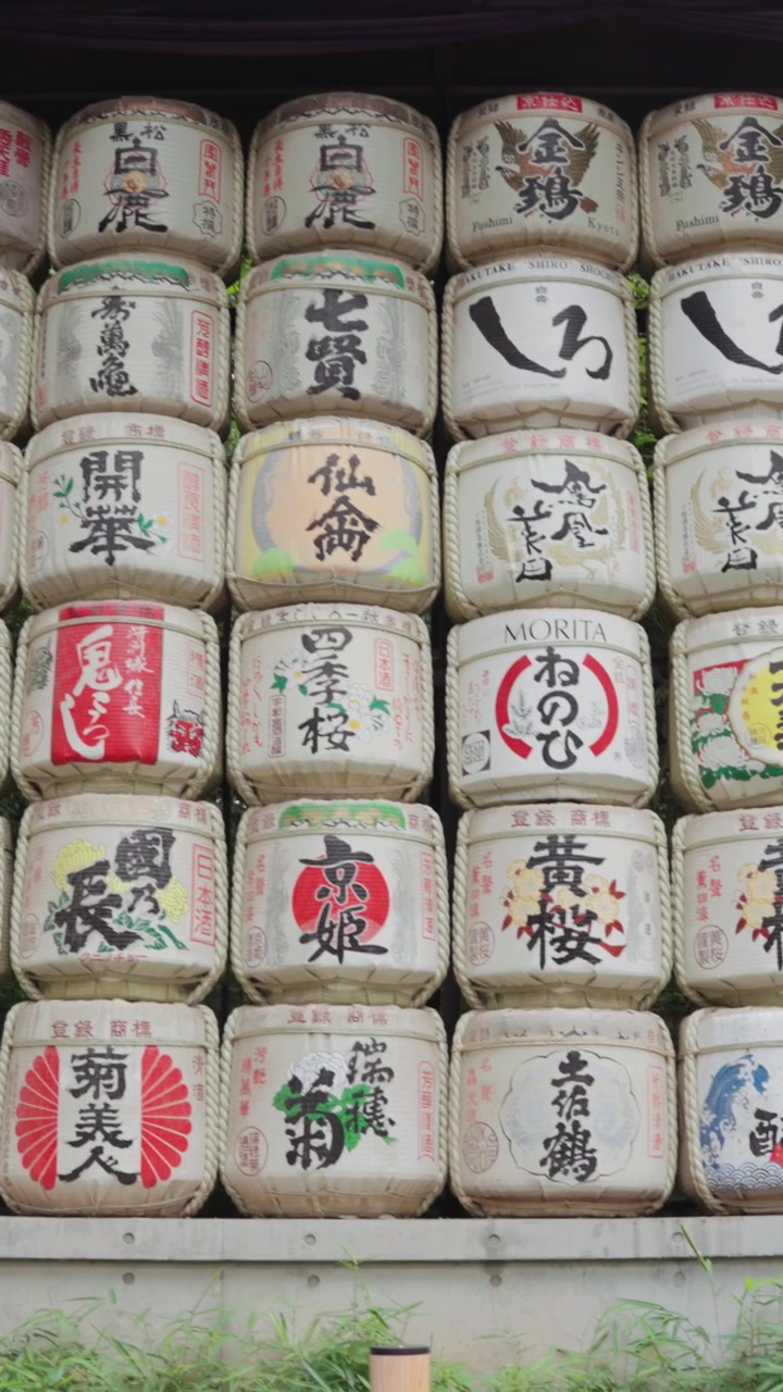 Vertical wide panning video of beautifully decorated sake barrels at Meiji Jingu Shrine during the daytime in Yoyogi Park in Tokyo.