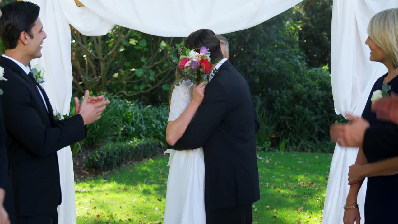 Sposi felici e sorridenti che si abbracciano e la gente applaude 4K 4k