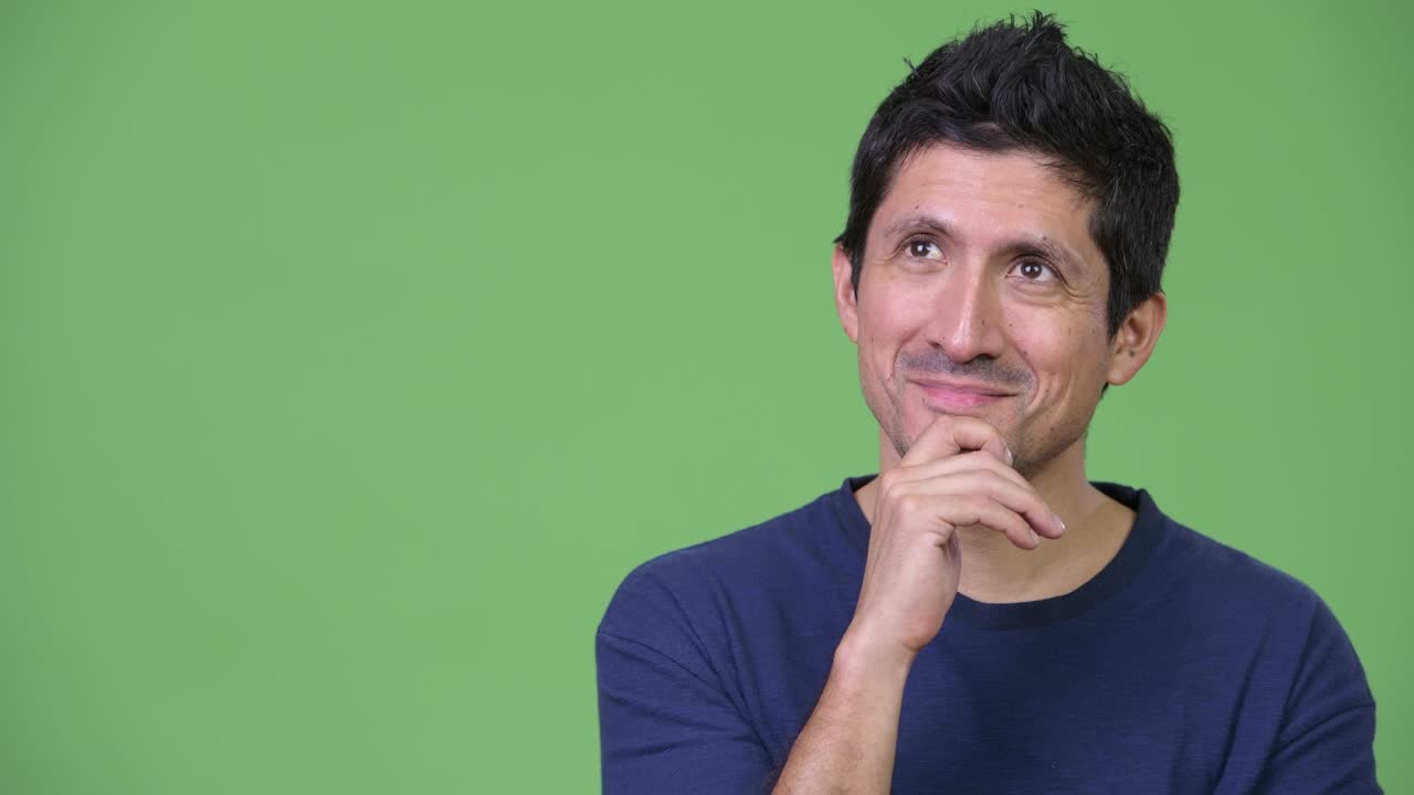 Hispanic man thinking against green background
