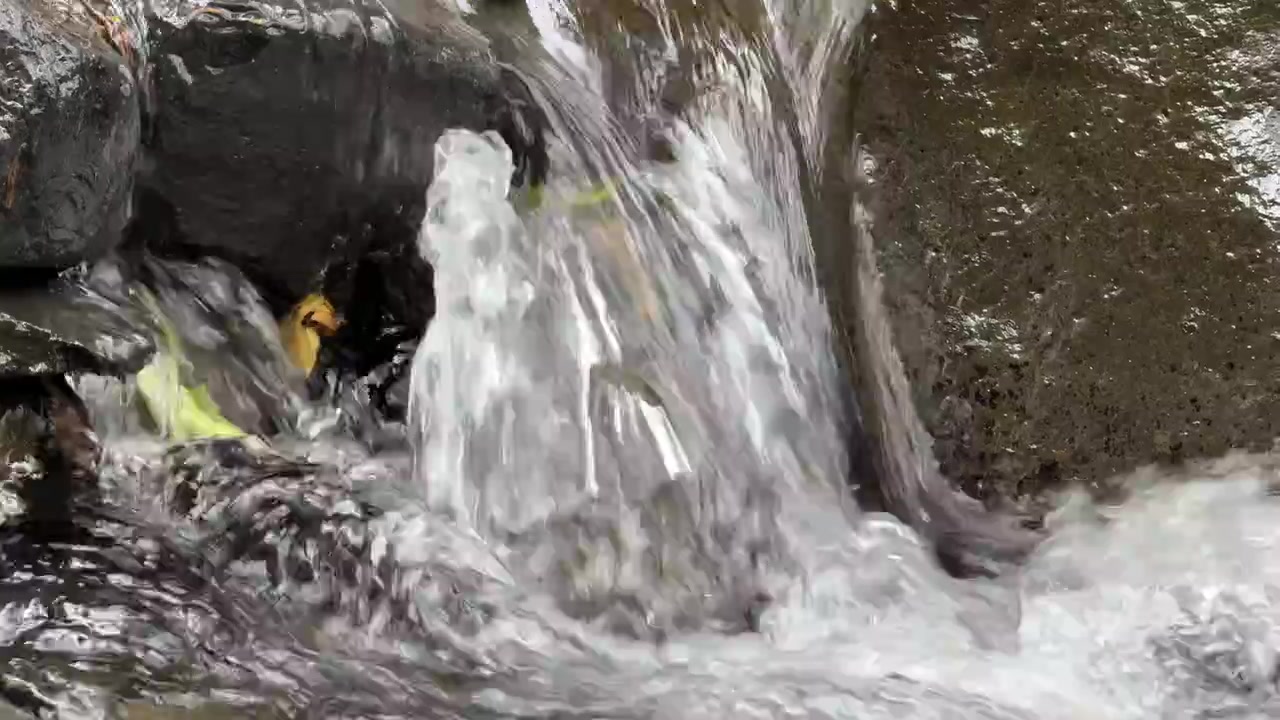Small Waterfall Flowing Over Dark Rocks in Nature
