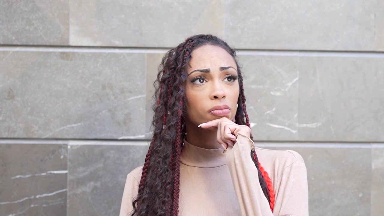 A confident woman is posing elegantly against a sleek modern wall showcasing her style and grace