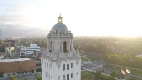 stunning pan around aerial shot of beverly hills building with palm trees during sunset