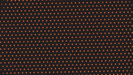 an eye-catching black and orange polka dot grid pattern on a dark background. the dots are small, evenly spaced, forming a symmetrical and uniform design