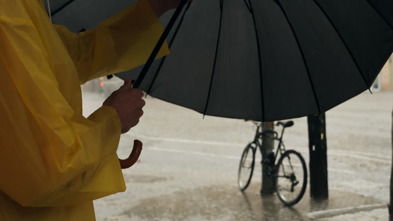 Business man tourist person with umbrella and raincoat on rainy european city street, lights reflecting, walking in Barcelona or Amsterdam during the rain