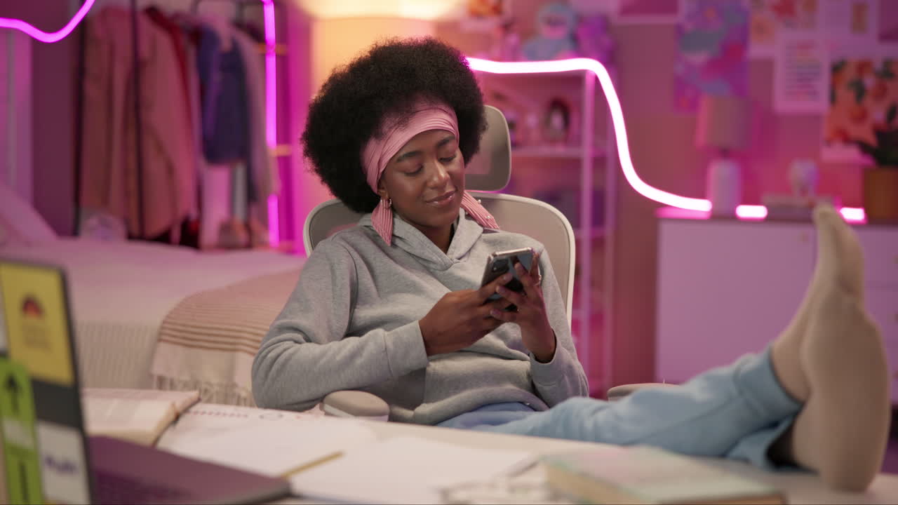 joven sonriendo mientras mira su teléfono en su dormitorio