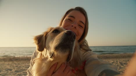 view from the side of the phone, a blonde girl and her light dog take a selfie on the background of a sunny beach in the morning, close-up shot