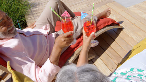 high angle view of black senior couple relaxing on pool deck chair in back yard of their home 4k