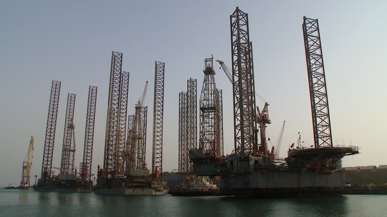 Langsom zoom ud af olieboreplatforme i havn, der afventer reparation og vedligeholdelse på tørdokken i Hidd, Bahrain