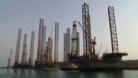 slow zoom out of oil rigs at port awaiting repair and maintenance at the dry dock in hidd, bahrain