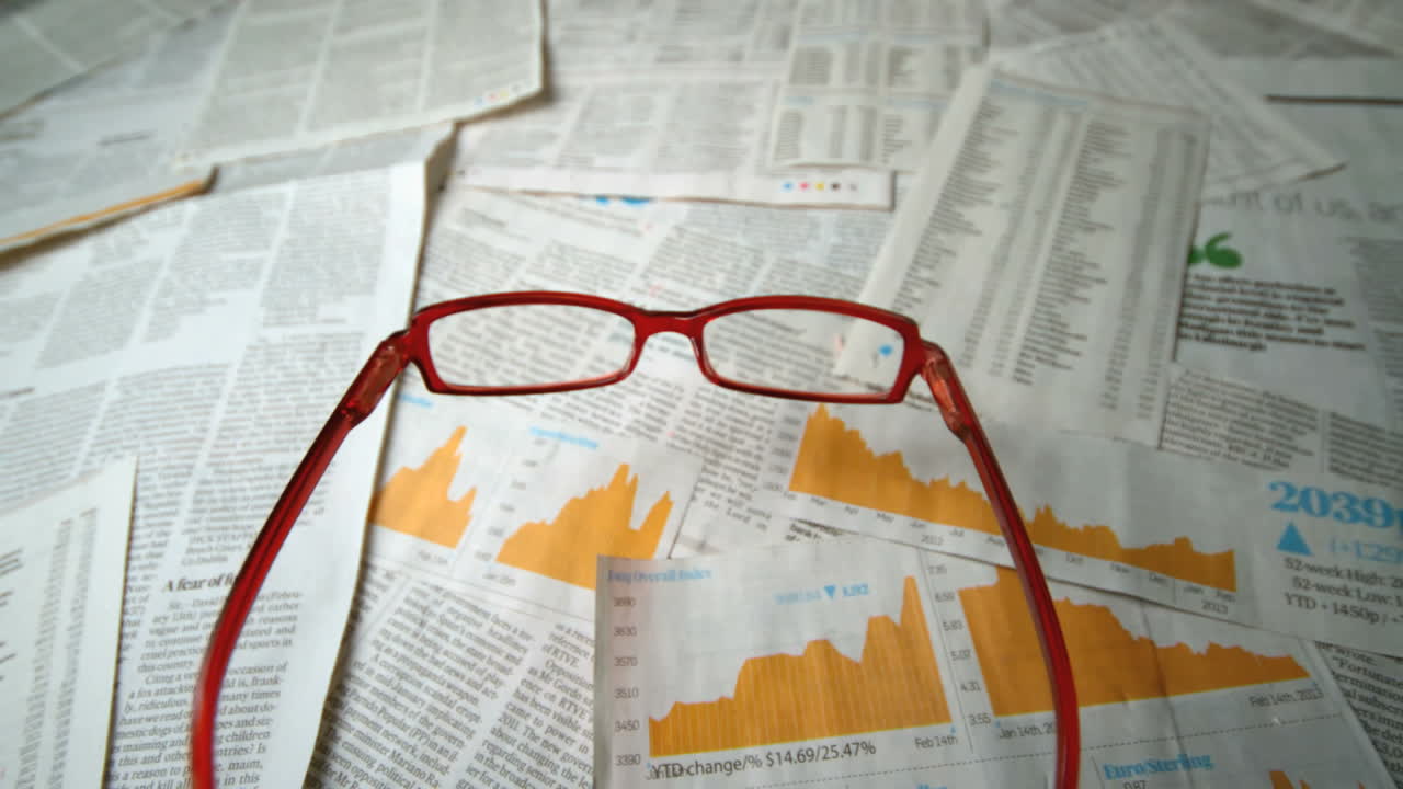 Glasses falling over sheets of paper showing yellow charts