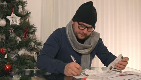 malestar frío macho ansioso clasificación montón de facturas y finanzas en el ordenador portátil en navidad