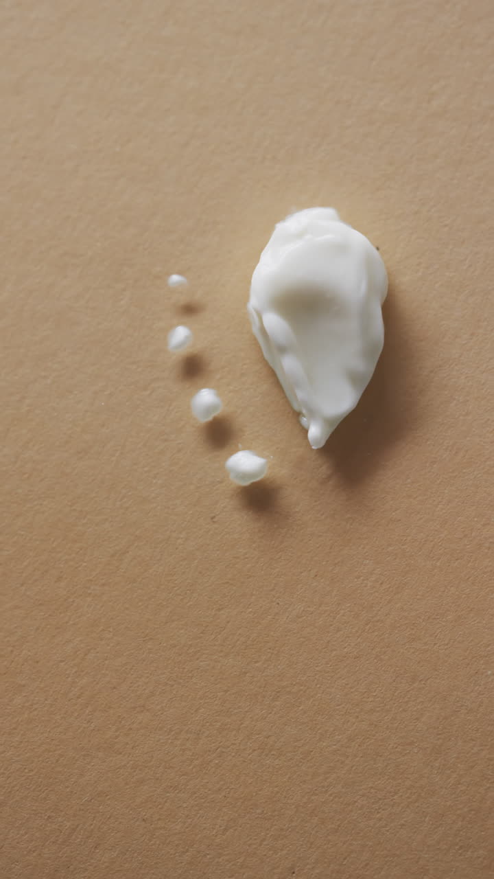 Vertical video of beauty product cream smudges with copy space on yellow background