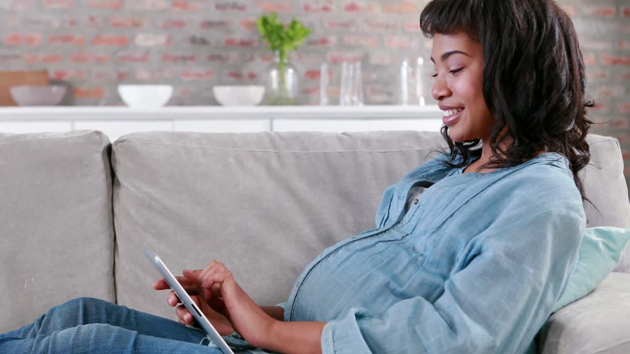 Happy pregnant woman using tablet pc