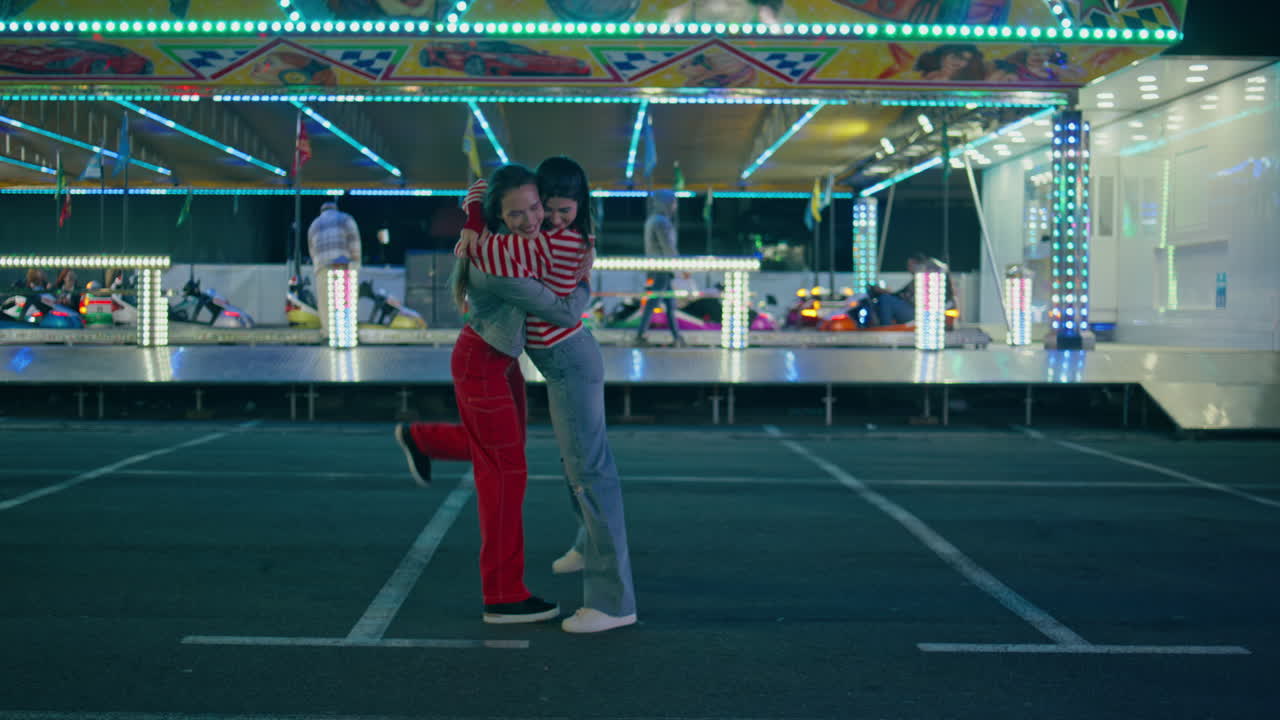 amigos adolescentes se reúnen en la noche de la feria. chicas felices caminando abrazadas en luna park.