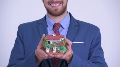 retrato de un feliz hombre de negocios barbudo con una estatuilla de la casa