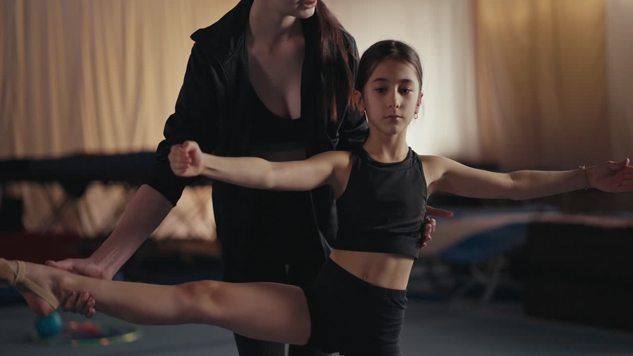 Young girl gymnast stretching with her coach