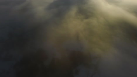 Drone-shot-of-an-incredible-landscape-covered-under-the-fog-with-surrounding-mountains-in-the-morning-at-winter-time-in-Slovenia-captured-in-4k,-drone-going-forward-with-the-camera-tilting-up