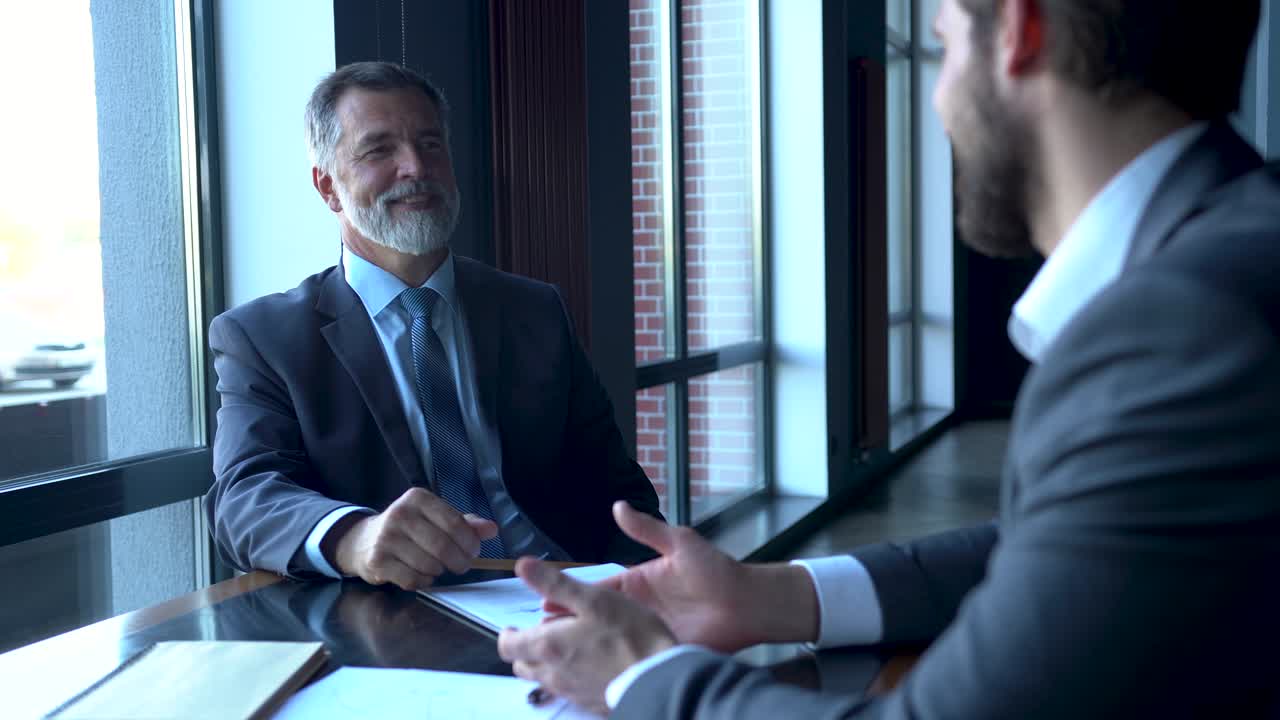 Business partners meeting in office building lobby and greeting with handshake