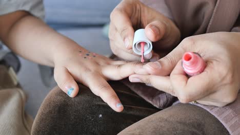 little girl getting her nails painted by her mom