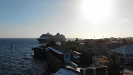 Cruise-ship-liner-docked-outside-of-Willemstad-backlit-by-sun-high-in-sky