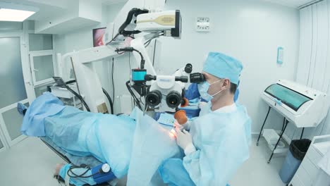 surgeon looking into the microscope at the eye of female patient at the operating room. doctor using microscope during eye surgery process, treatment of cataract and diopter correction.