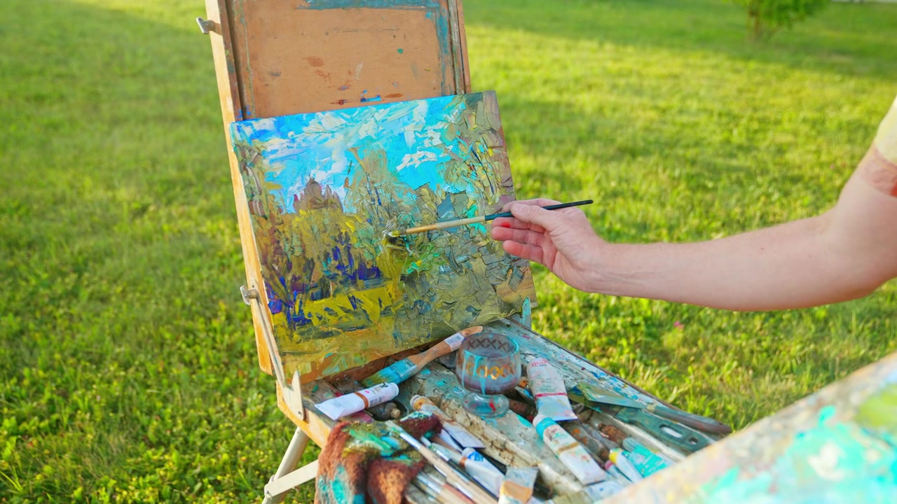 Artista che dipinge un paesaggio colorato su un cavalletto all'aperto
