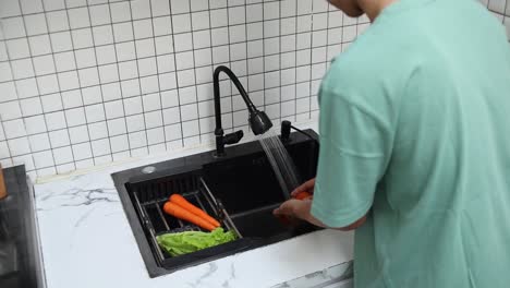 person washing vegetables in a kitchen sink