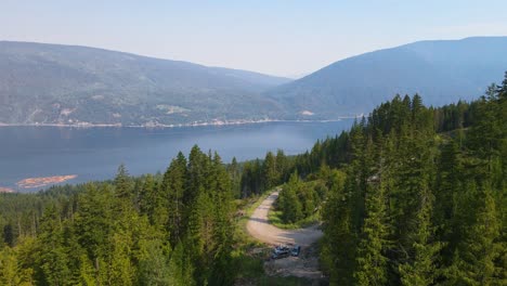 Aerial-dolly-in-of-vibrantly-coloured-conifers-towering-above-a-blue-lake-in-British-Columbia