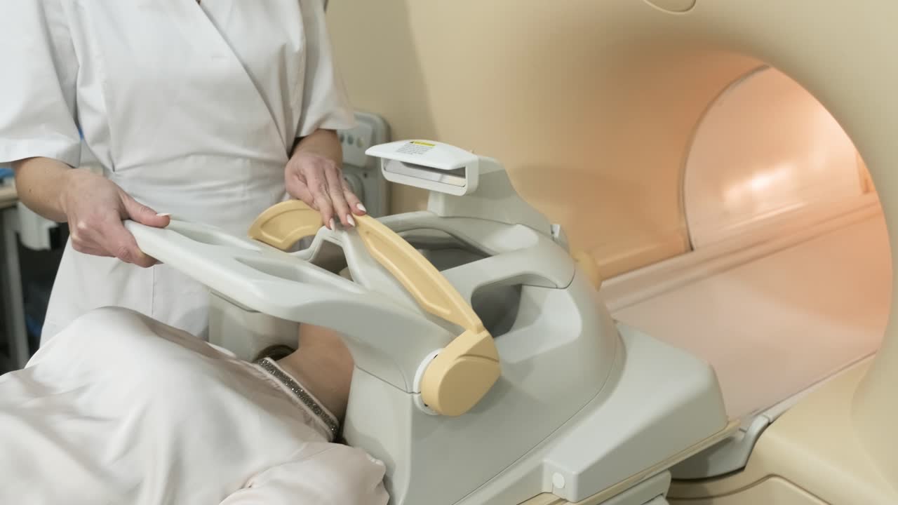 la mujer radióloga hace escaneo de resonancia magnética del cerebro, la cabeza, el cuello. la joven paciente femenina en la mesa automática entra en una máquina de resonanza magnética de tipo cerrado utilizando equipos modernos, bobina en la cabeza del paciente.