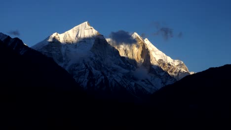 Time-lapse-from-sunrise-to-sunset-of-clouds-rolling-and-flowing-over-peaks-of-the-Himalayan-Range,-Upper-Hilayan-Belt,-Uttarakhand,-India-with-beautiful-blue-sky-background