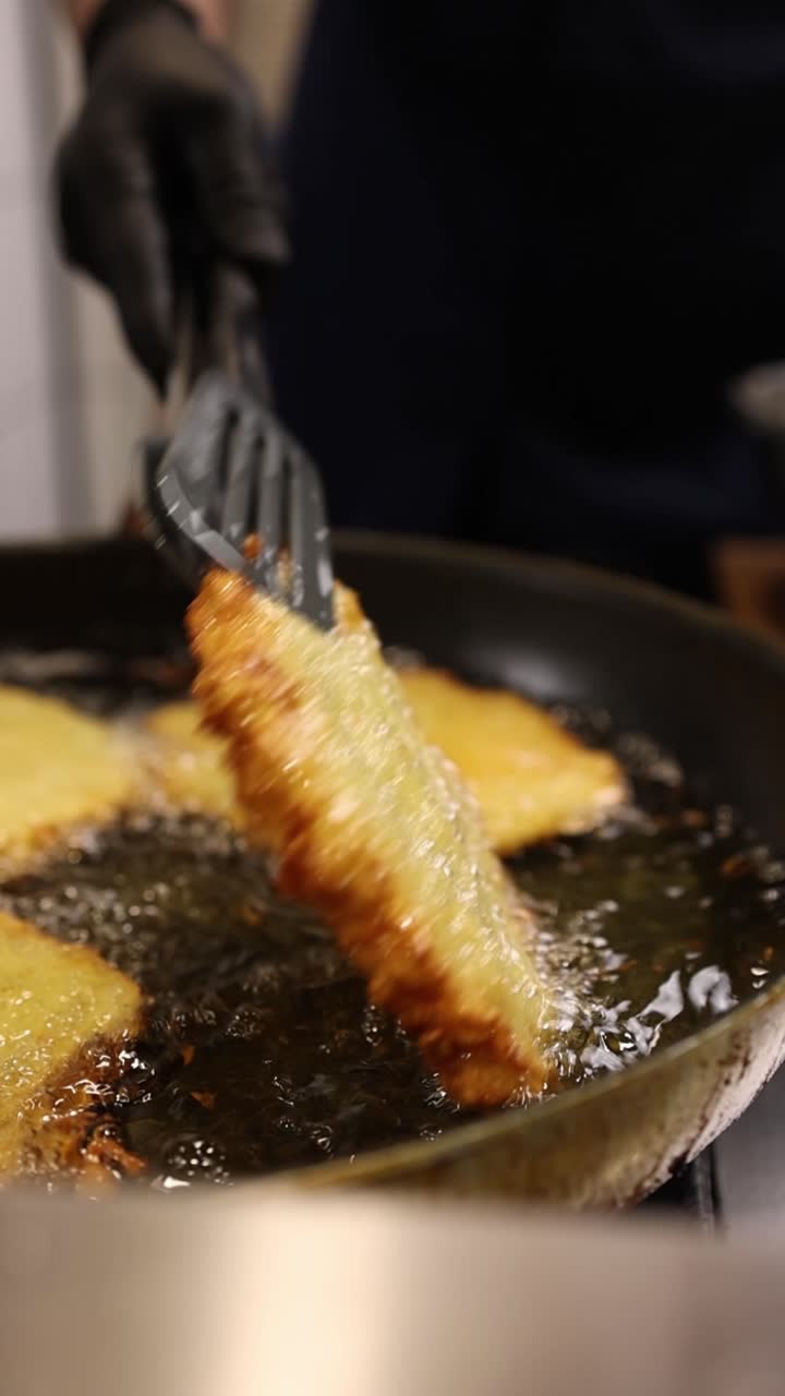 Kok steger gyldne kartoffelpandekager i varm olie