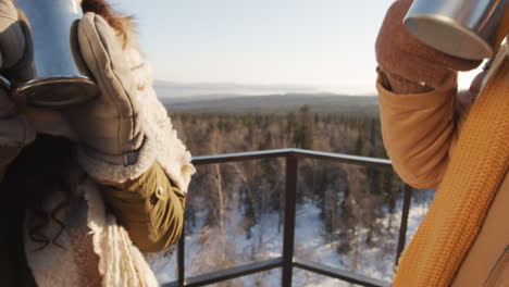 friends enjoying hot drinks on a winter mountaintop view