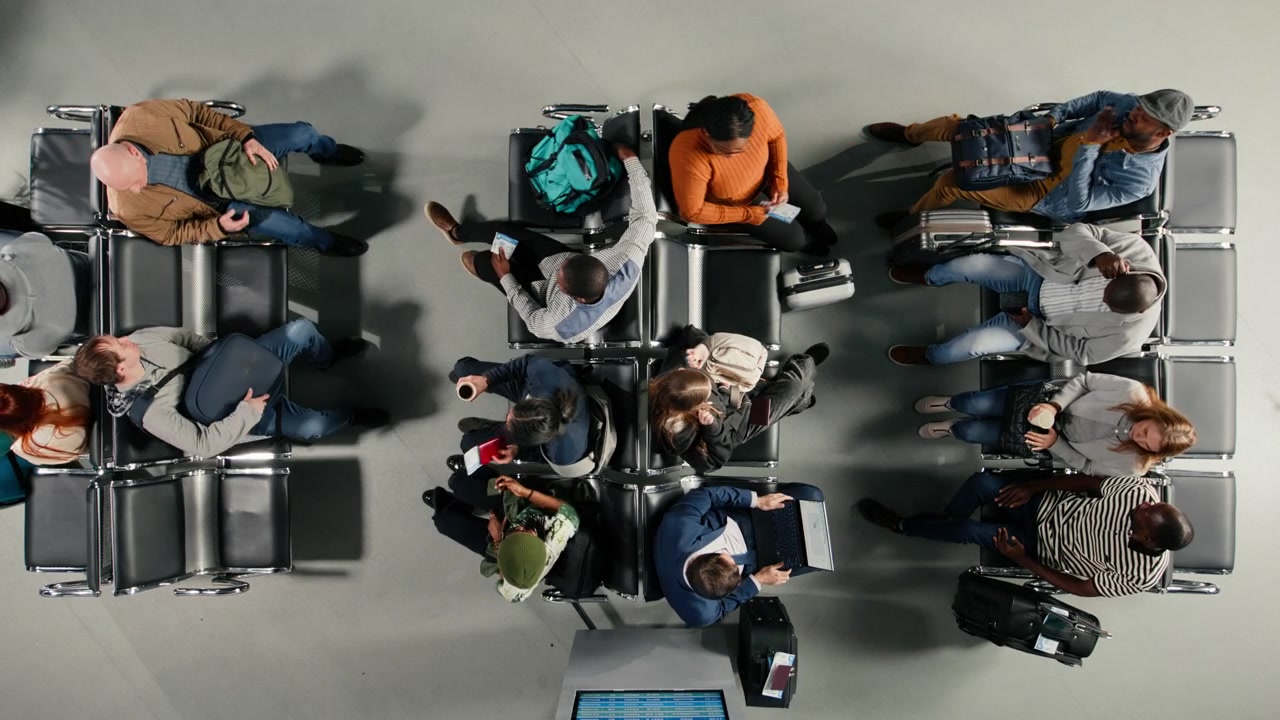 Chatting, top down view and multiracial tourists in busy airport lounge sitting