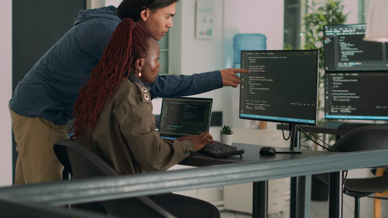 Two software coders analyzing source code on computer and laptop screen